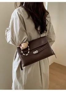 Detail view of brown PU leather shoulder bag with silver buckle and bear charm