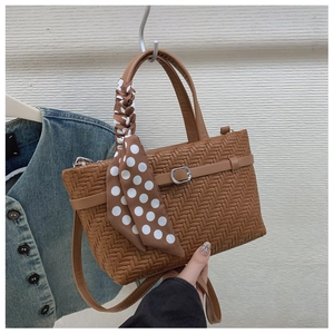 Close-up of brown woven texture handbag with polka dot scarf and crossbody strap