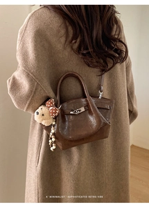 Close-up of brown leather bucket bag with cute plush bear charm and beaded chain detail
