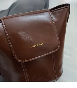 Detail of the golden YNGE & VIER logo on dark brown oil wax leather handbag