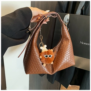 Detailed woven texture of brown hobo bag featuring a playful plush monster charm