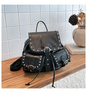 Détail du sac à dos en similicuir noir avec rivets argentés et fermeture à boucle