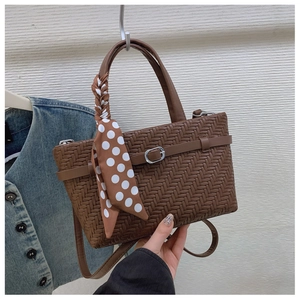 Detail of coffee brown woven tote bag featuring a polka dot silk scarf and silver buckle