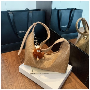 Detail of woven texture on brown faux leather tote bag with a cute plush charm