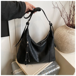 Détail du sac cabas en cuir noir avec poche à franges rivetées et bandoulière réglable