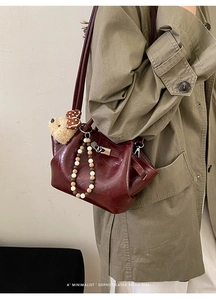 Close-up of wine red patent leather bucket bag with teddy bear charm and beaded handle