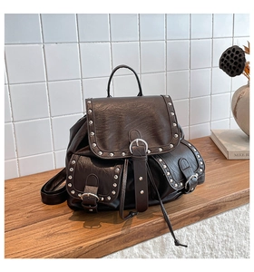 Détail d'un sac à dos vintage marron foncé avec clous argentés et texture cuir poli