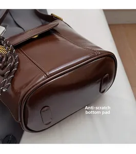Detail of a dark brown glossy leather bucket bag showing protective base studs for durability
