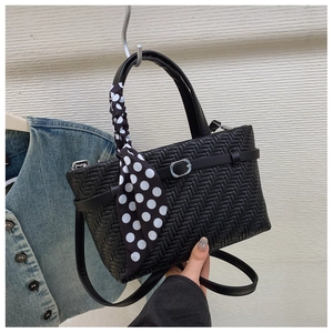Detail of black woven leather handbag featuring silver buckle and polka dot silk scarf