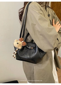 Detail of black pleated leather bucket bag with cute plush bear and beaded charms