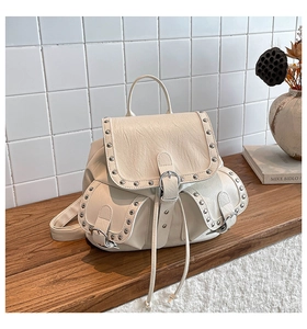 Détails du sac à dos en cuir crème avec clous argentés et deux poches sur le devant