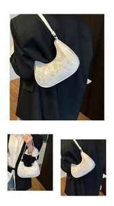 Detailed view of white half-moon bag featuring 3D butterfly lace and silver hardware