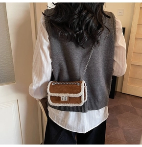 Close-up of brown suede crossbody bag with white faux shearling trim and metal chain strap