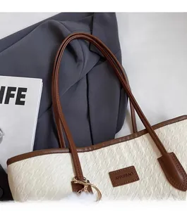 Detail of cream tote bag with houndstooth texture, brown trim and plush charm