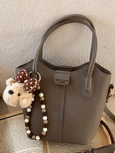 Modische taupefarbene Eimer-Tasche aus Leder mit niedlichem Teddybär-Anhänger