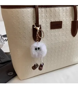 Macro detail of white plush cartoon keychain accessory on a houndstooth tote bag