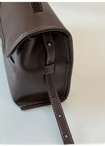 Detailed close-up of dark brown leather strap with adjustable holes and white stitching