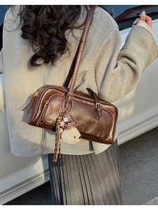 Detail of vintage brown bowling bag with plush bear charm and leather tassel on model