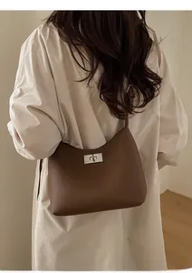 Detail of a brown lychee pattern leather shoulder bag with a silver twist lock buckle
