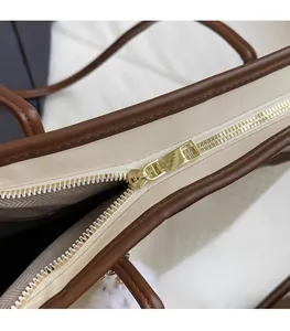 Detail of premium bicolor tote bag featuring a smooth gold metal zipper and leather edges
