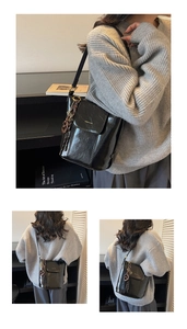Close-up of black glossy leather bucket bag with flap closure and woven chain detail