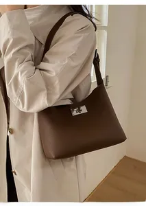 Detailed view of dark brown pebbled leather shoulder bag featuring silver rotating lock closure