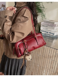 Detail of red vintage bowling bag with cute bear charm and gold hardware on shoulder strap