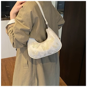 Detail shot of the white crescent bag featuring 3D butterfly embroidery and fine texture