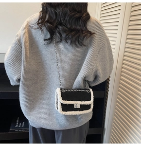 Detail showing monochrome chain bag with white faux fur trim on grey knit sweater
