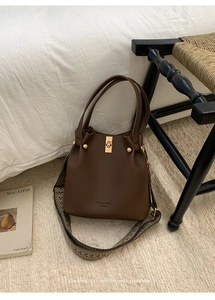 Detail of brown litchi pattern leather bucket bag with jacquard strap and gold metal lock