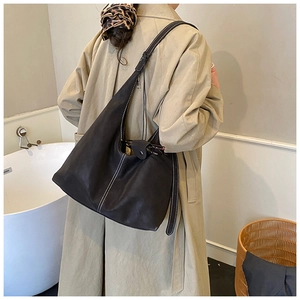 Détail d'un sac hobo noir avec surpiqûres blanches porté par un mannequin en intérieur