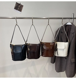 Detail of trendy bucket bags in black, coffee, brown and white with tassel charms