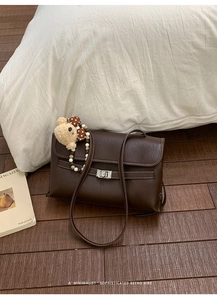 Close-up of brown retro shoulder bag with white stitching and silver metal buckle
