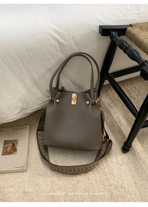 Close-up of taupe bucket bag showing litchi leather texture and retro jacquard strap