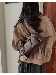 Detail of vintage brown PU bowling bag with white plush puppy charm and zipper pocket