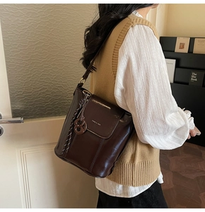 Detail of dark brown vintage bucket bag with polished leather finish and gold branding