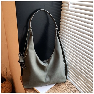 Gros plan sur les coutures contrastées d'un grand sac hobo gris-vert en daim mat