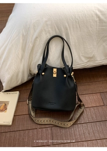Detail of black lychee grain leather bucket bag with vintage geometric woven strap