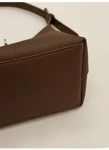 Close-up of the thick reinforced base and lychee grain leather texture of the brown bucket bag