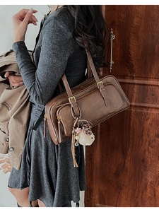 Close-up of a vintage brown leather bowling bag with double zippers and sheep pendant