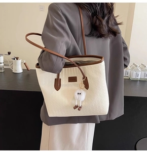 Detail of the woven texture and brown leather trim on a minimalist off-white tote bag