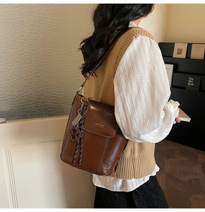 Close-up of dark brown glossy bucket bag with golden hardware and brand logo detail