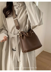 Close-up of dark brown lychee texture bucket bag with colorful woven shoulder strap