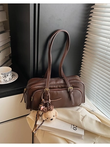 Detail of dark brown faux leather bowling bag with cute plush puppy charm and golden hardware