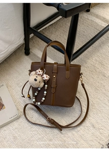 Close-up of deep brown litchi textured bucket bag with teddy bear and beaded charms