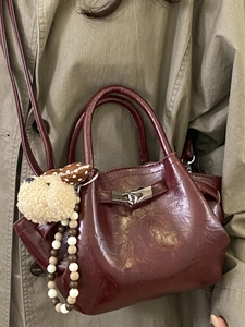 Minimalist wine red bucket bag with plush charm and silver twist lock in hand-held style