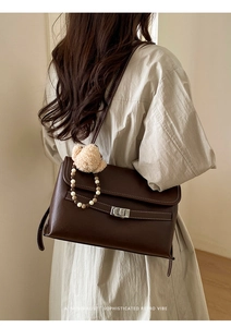 Model wearing dark brown vintage leather shoulder bag with a cute plush bear pendant