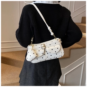 Detailed view of white polka dot shoulder bag with heart charm and gold metal buckles