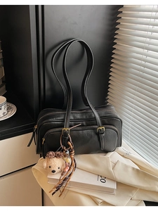 Detail of vintage black bowling bag with multi-zipper pockets and cute plush bear charm