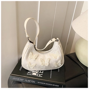 Detailed view of 3D lace butterfly appliqués on a white luxury aesthetic hobo bag
